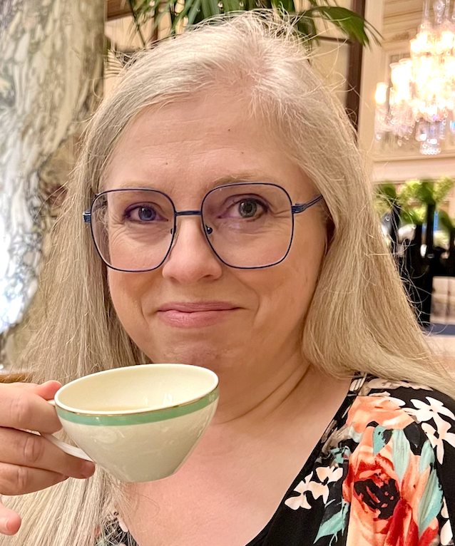 A picture of Susan Langley holding a cup of tea and smiling